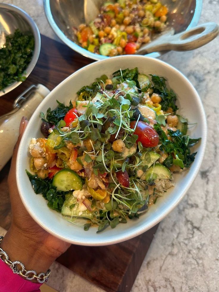 a person holding a bowl filled with vegetables