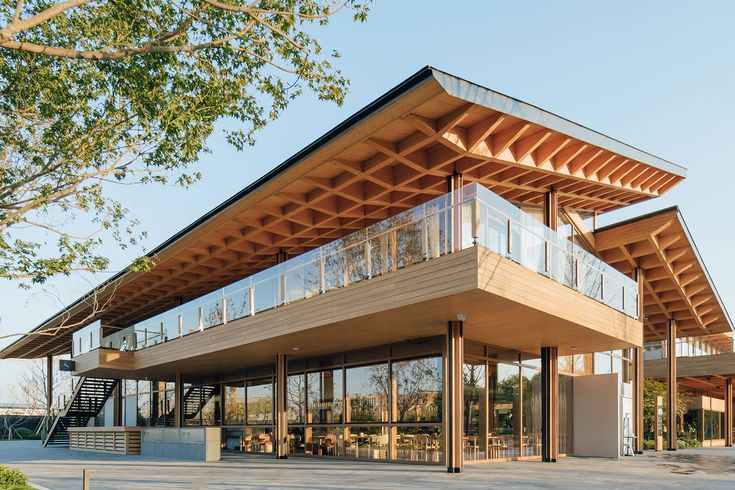 a large wooden building with lots of windows on the top and bottom floor, in front of some trees