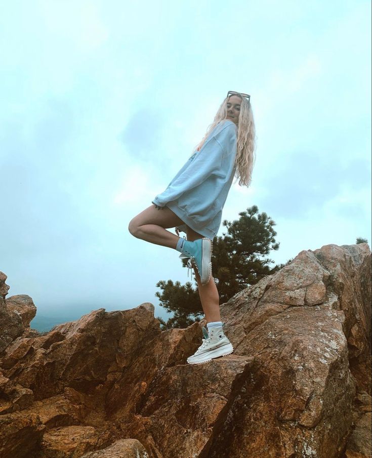 a woman standing on top of a large rock