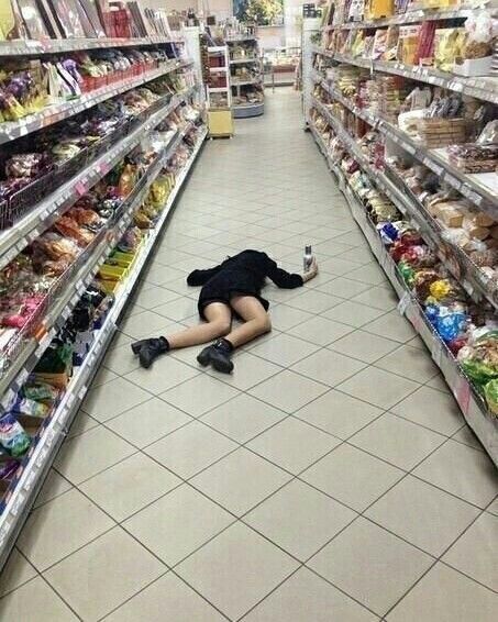 a person laying on the ground in a grocery store aisle with their legs crossed and head down