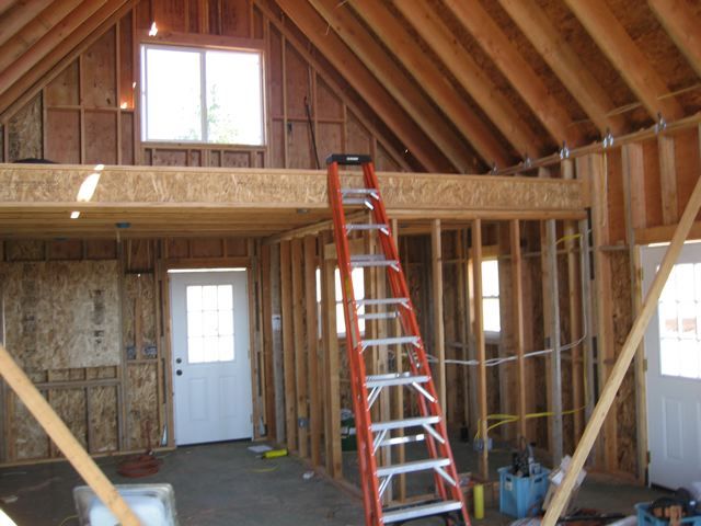 a ladder is in the middle of a room being built with wooden walls and beams