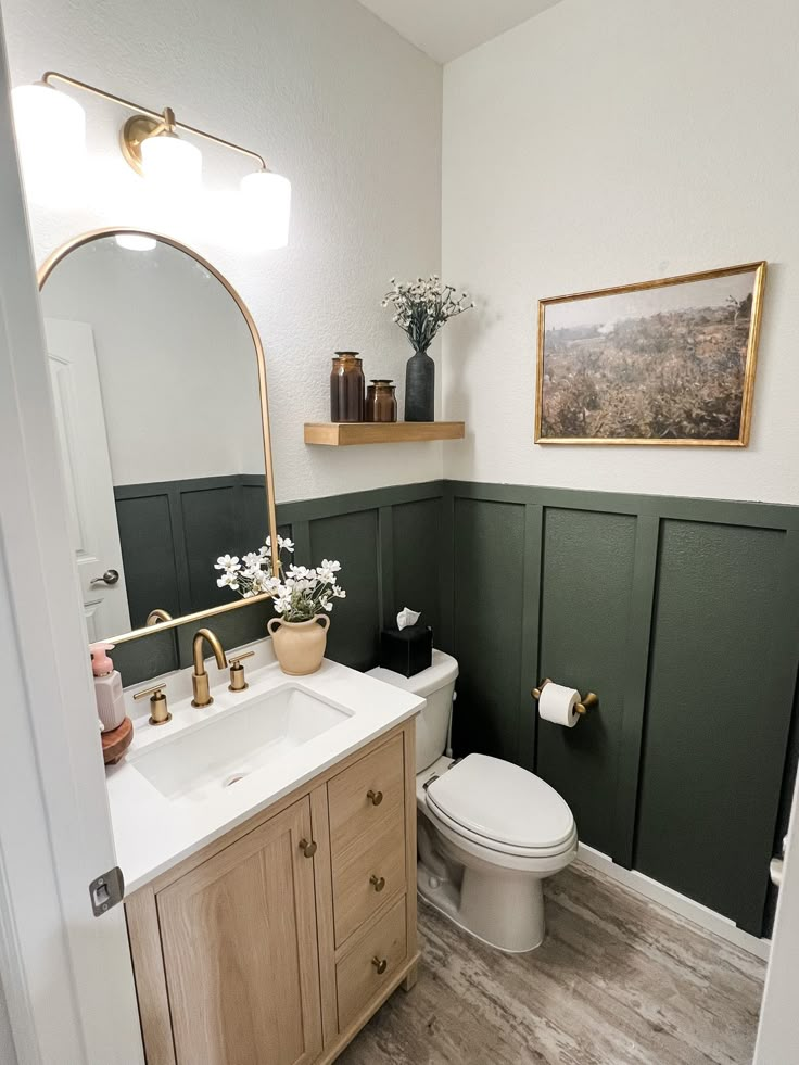 a white toilet sitting next to a sink in a bathroom under a large mirror above it