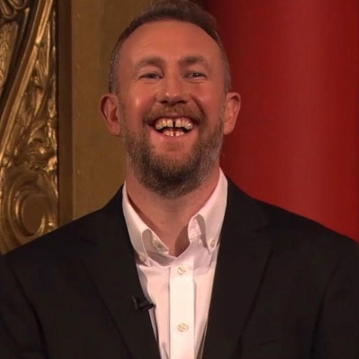 a smiling man in a black suit and white shirt