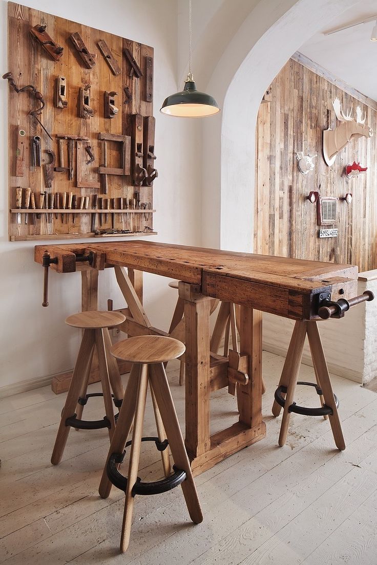 a wooden table with two stools in front of it and a wine rack on the wall