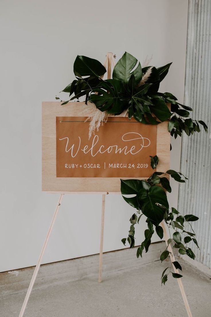 a welcome sign with greenery on it