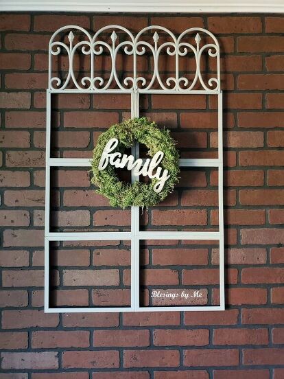 a wreath hanging on the side of a brick wall with a family sign in it