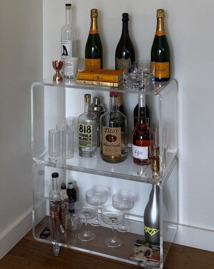 a shelf filled with lots of bottles and glasses on top of a hard wood floor