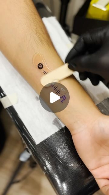 a person getting a tattoo on their arm with a tape around it's wrist