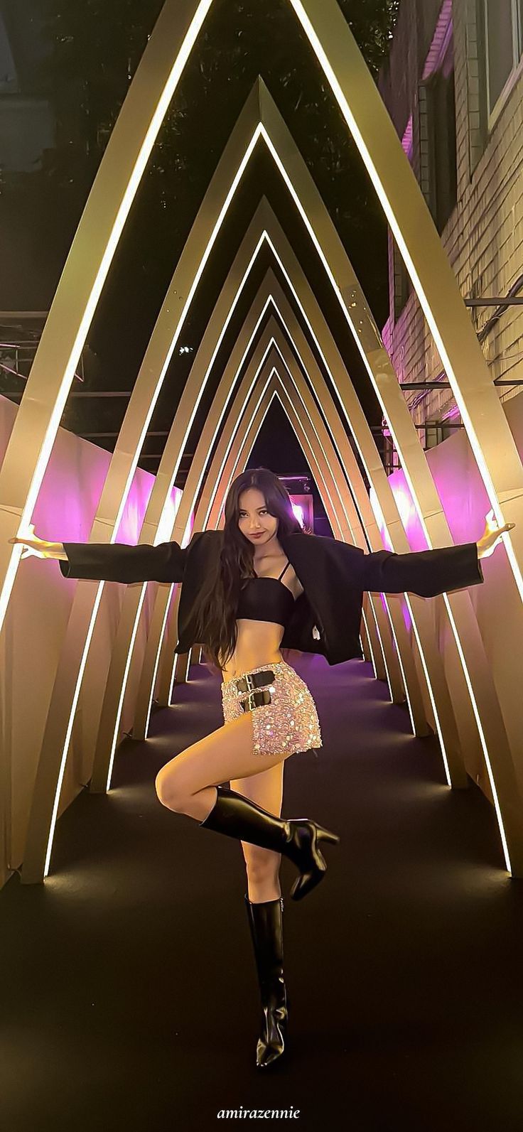 a woman is posing for a photo in front of an arch with lights on it