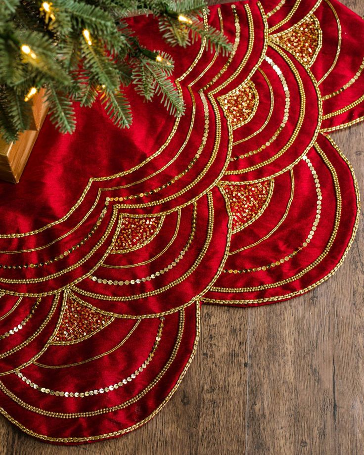 three red place mats with gold designs on them and a christmas tree in the background