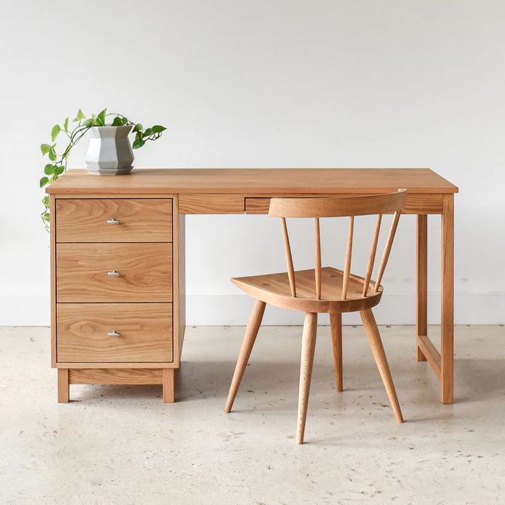 a wooden desk with two chairs and a vase on it's top, in front of a white wall