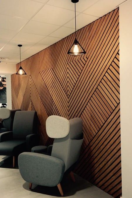 an office waiting area with chairs and lights on the wall, in front of a wood paneled wall