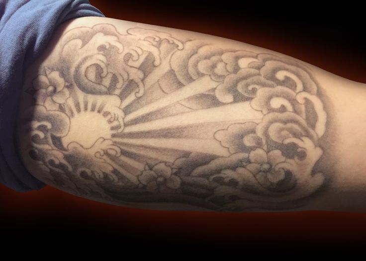 a man's arm with clouds and sun tattoo on it