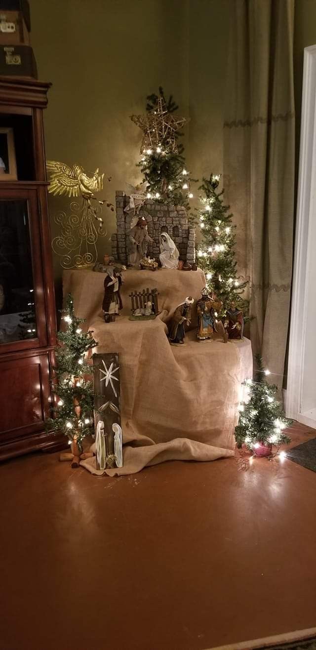 a christmas tree with lights and presents on the ground in front of it, surrounded by other decorations