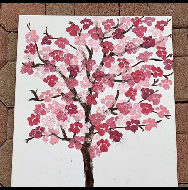 a painting of a tree with pink and red flowers painted on the outside of it