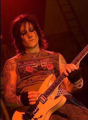 a man with long hair and tattoos playing an electric guitar in front of red lights