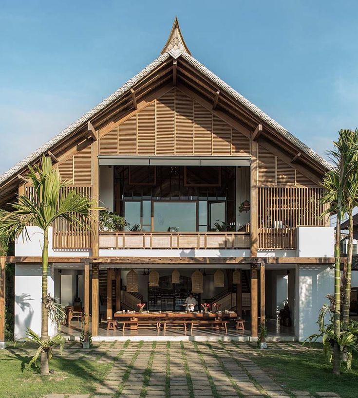 a large wooden building sitting on top of a lush green field next to palm trees