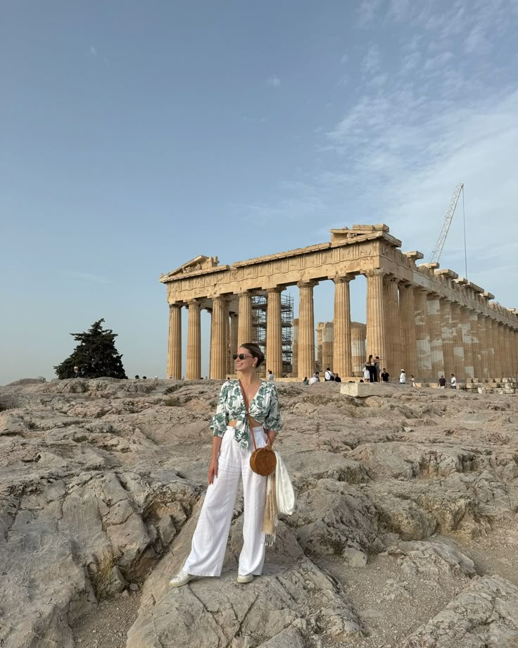 a woman standing on top of a rock covered hillside