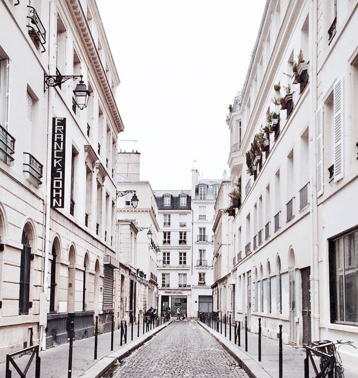 an empty cobblestone street lined with white buildings