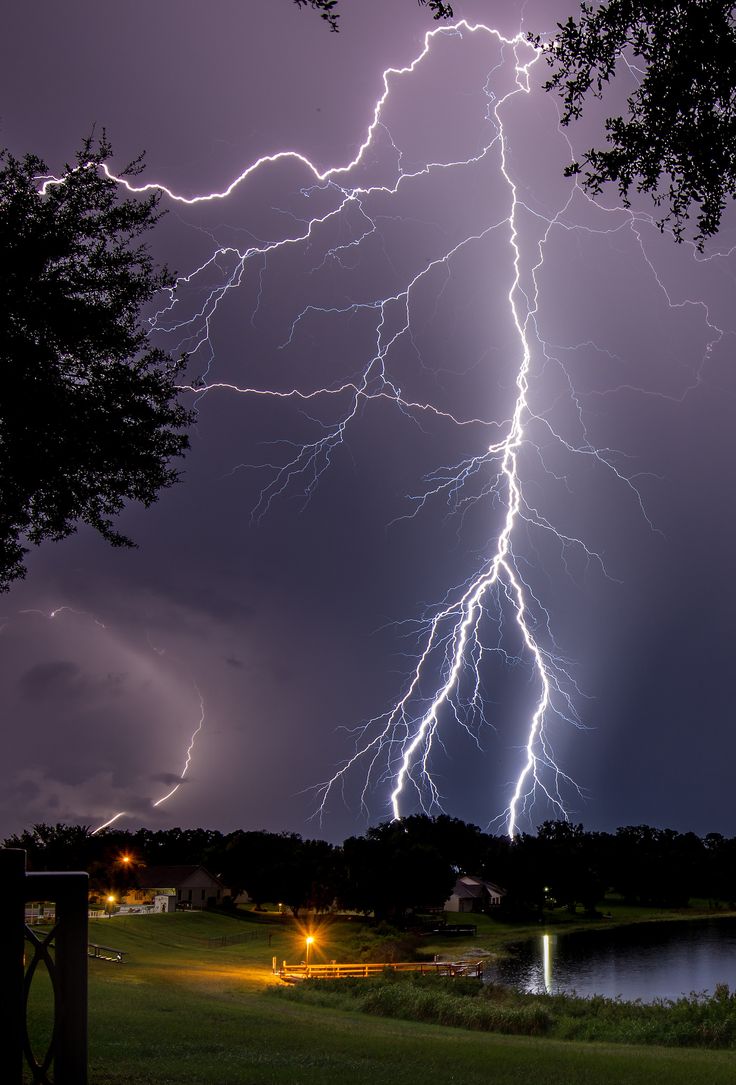 lightning strikes over a lake at night time