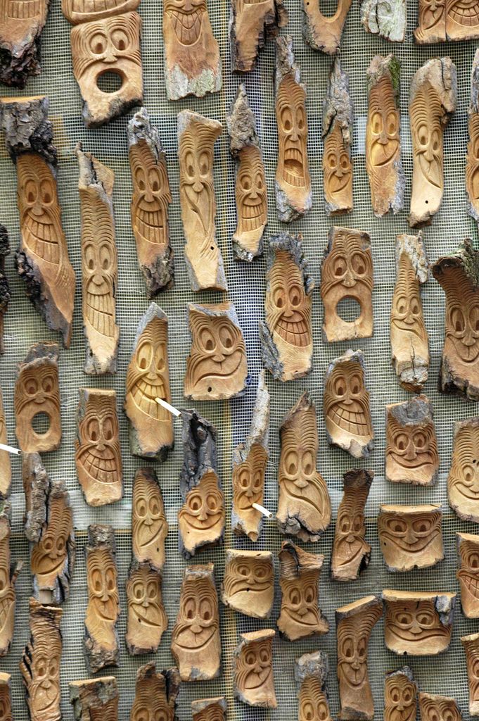 many carved wooden faces are displayed on the wall