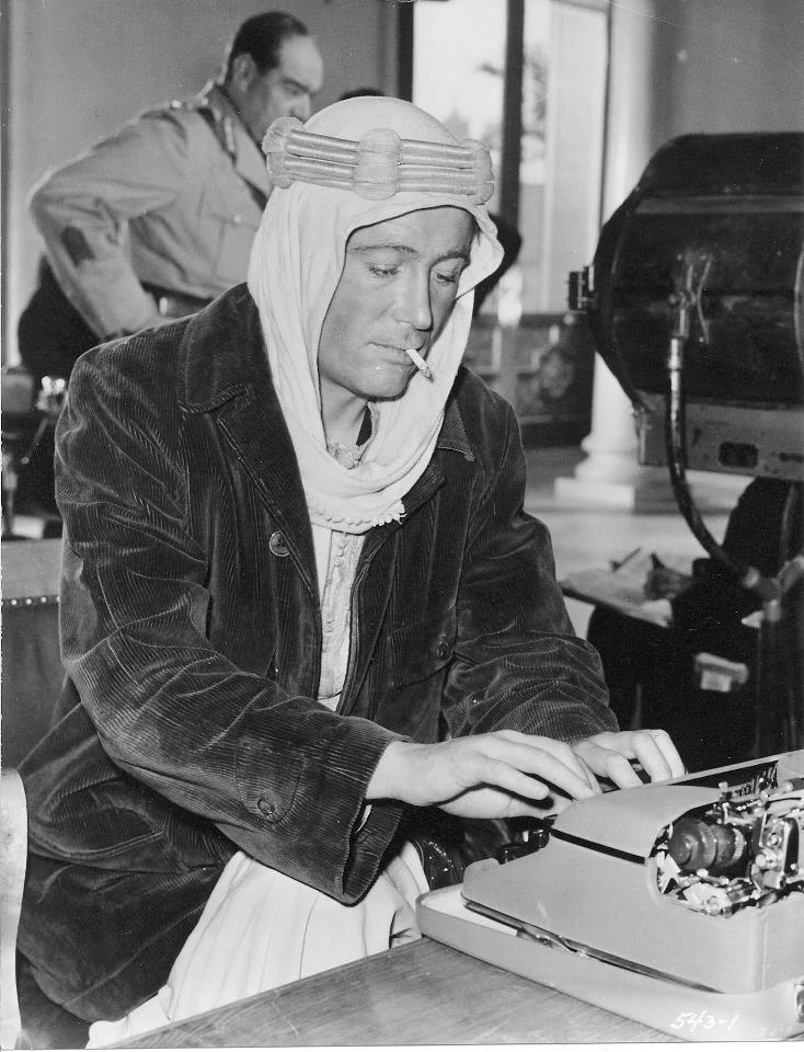 black and white photograph of a woman working on an old typewriter with two men in the background