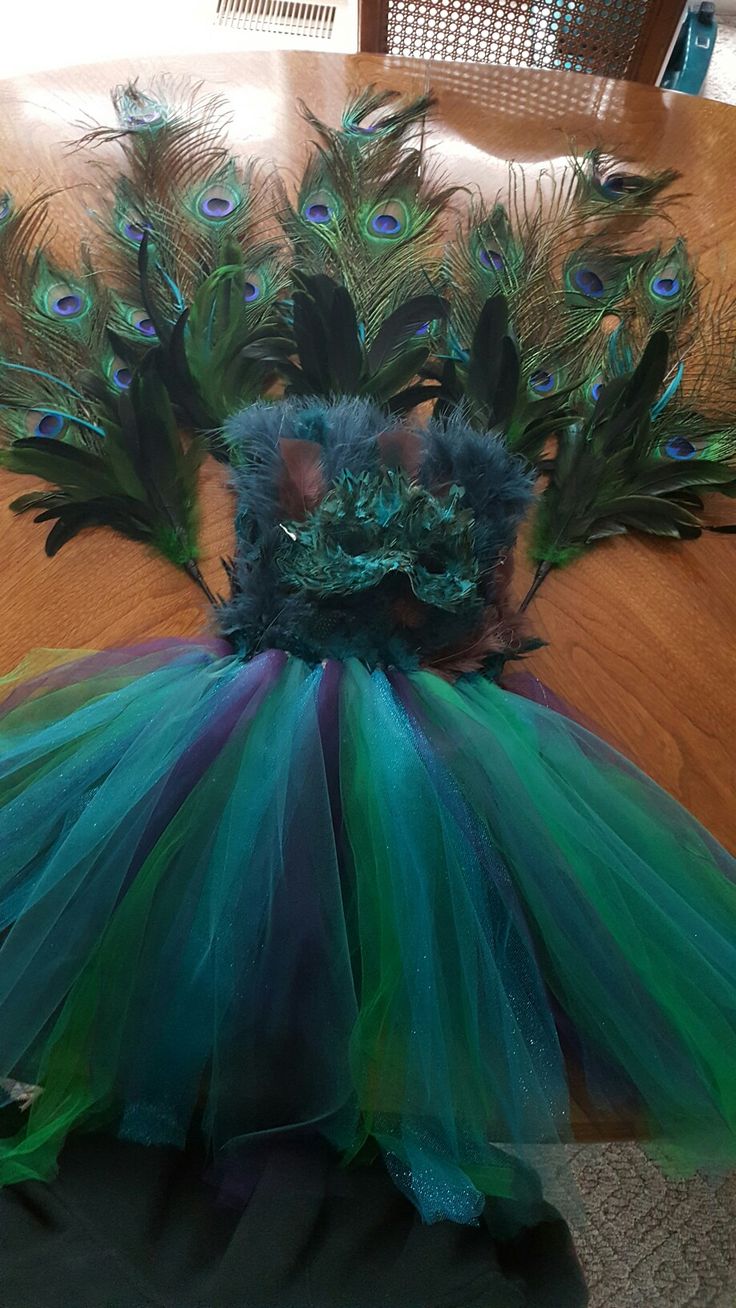 there is a green and blue tutu skirt on the floor next to some feathers