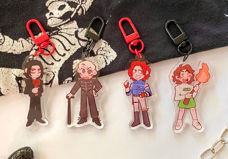 four keychains with cartoon characters on them sitting next to a pair of scissors