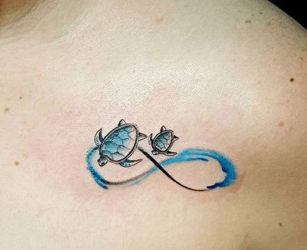 a tattoo on the back of a woman's shoulder with two turtles and an infinite symbol