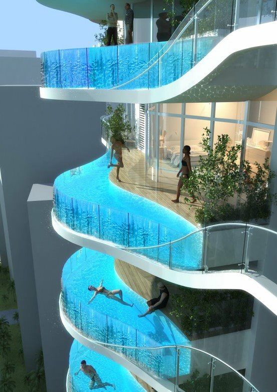 two people are swimming in a pool next to a tall building with glass balconies