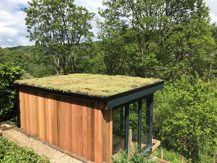 a small building with a green roof surrounded by trees