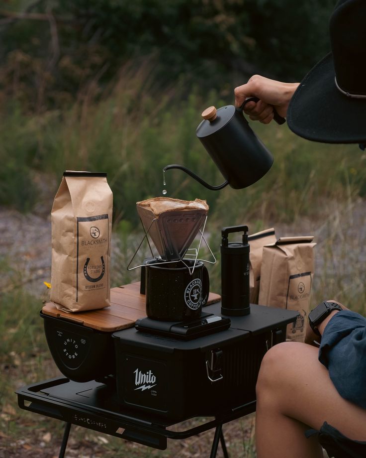 a person sitting at a table with some coffee bags and a grinder on it