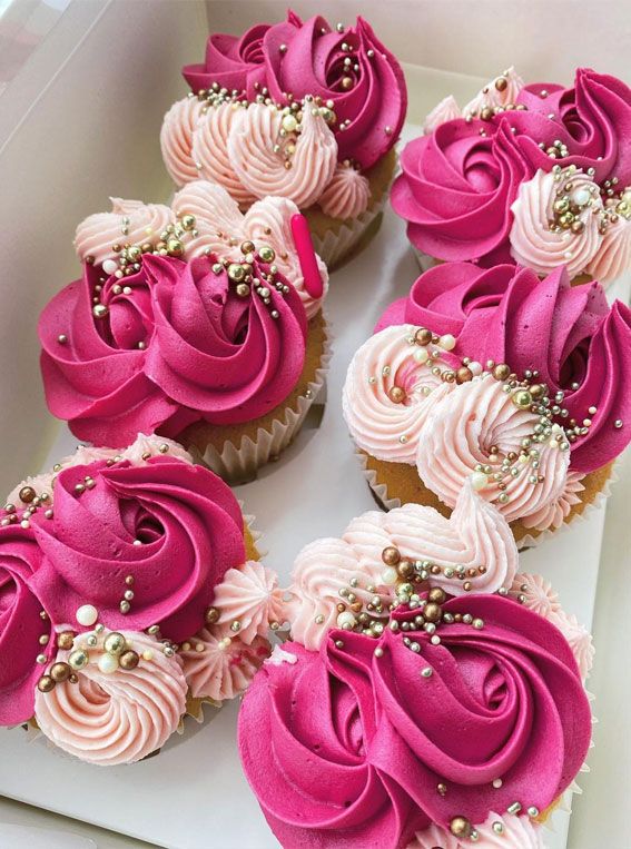 cupcakes decorated with pink and white frosting in a box