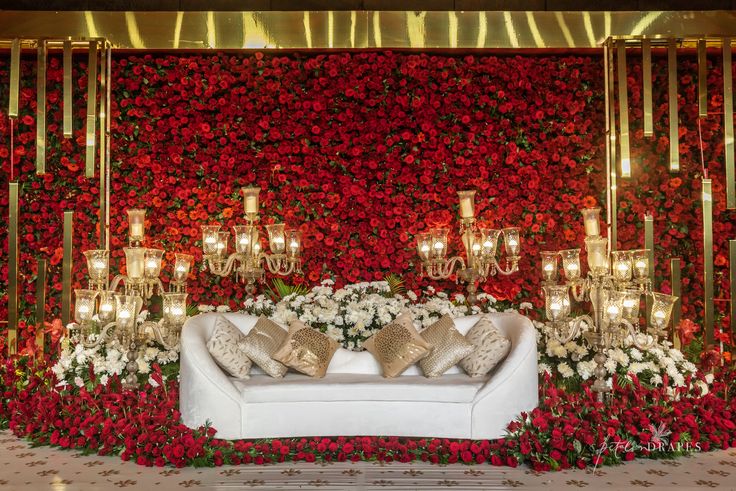 a white couch sitting in front of a flower covered wall with candles and flowers on it