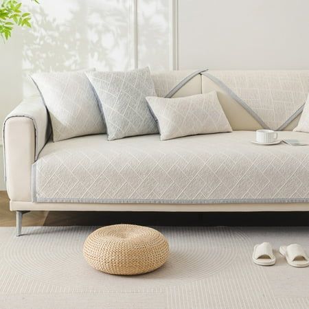 a white couch sitting on top of a wooden floor next to a potted plant