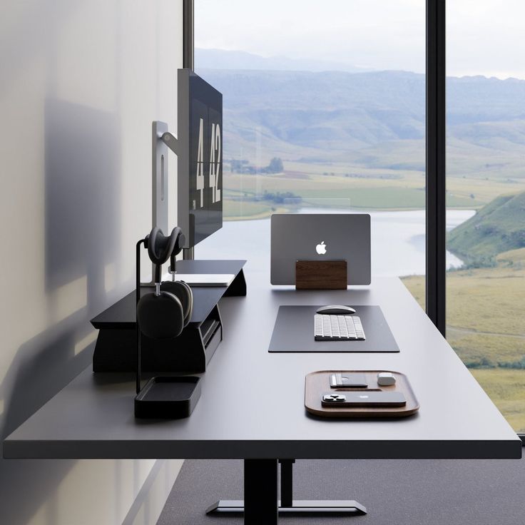 an apple computer sitting on top of a desk in front of a large glass window