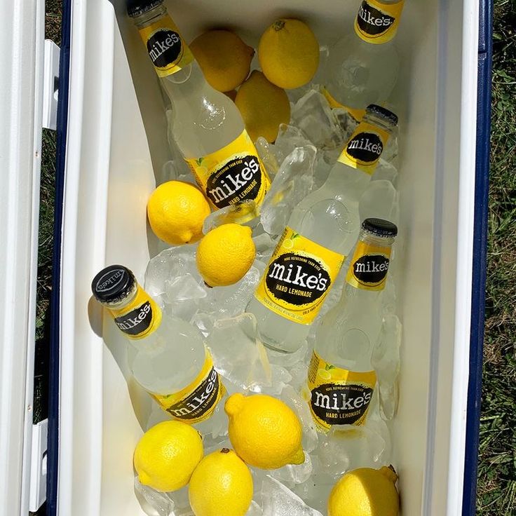 an open cooler filled with lemons and bottles of miller's water in the grass