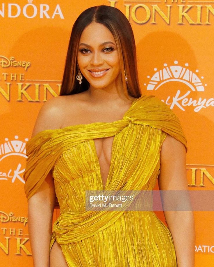 an image of a woman in a yellow dress at the lion king uk film premiere