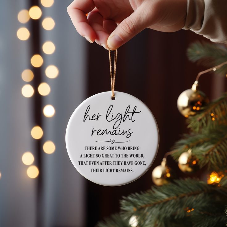 a person holding a christmas ornament that reads, her light remains there are some who bring a light so great to the world