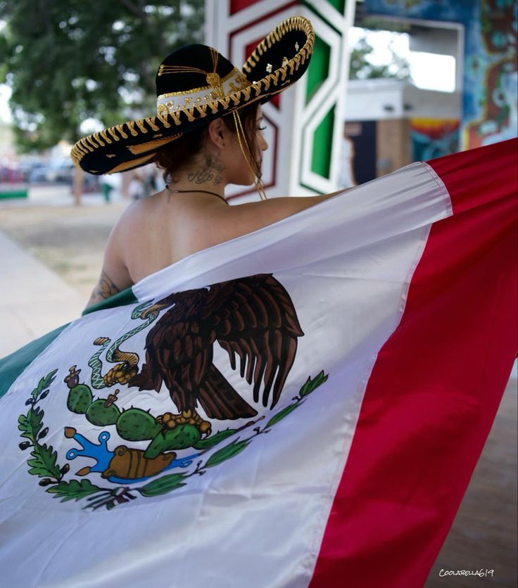 a woman wearing a sombrero and holding a mexican flag