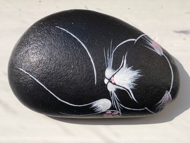 a black rock with a white cat painted on it