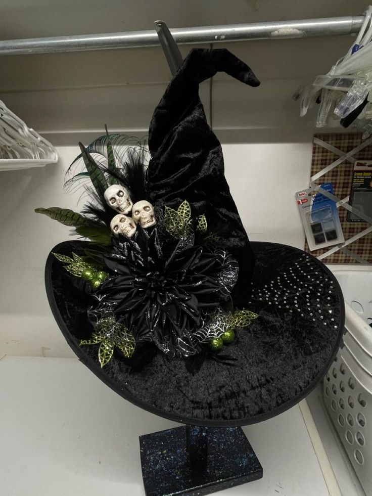 a black witches hat with skulls and flowers on the top is sitting on a shelf