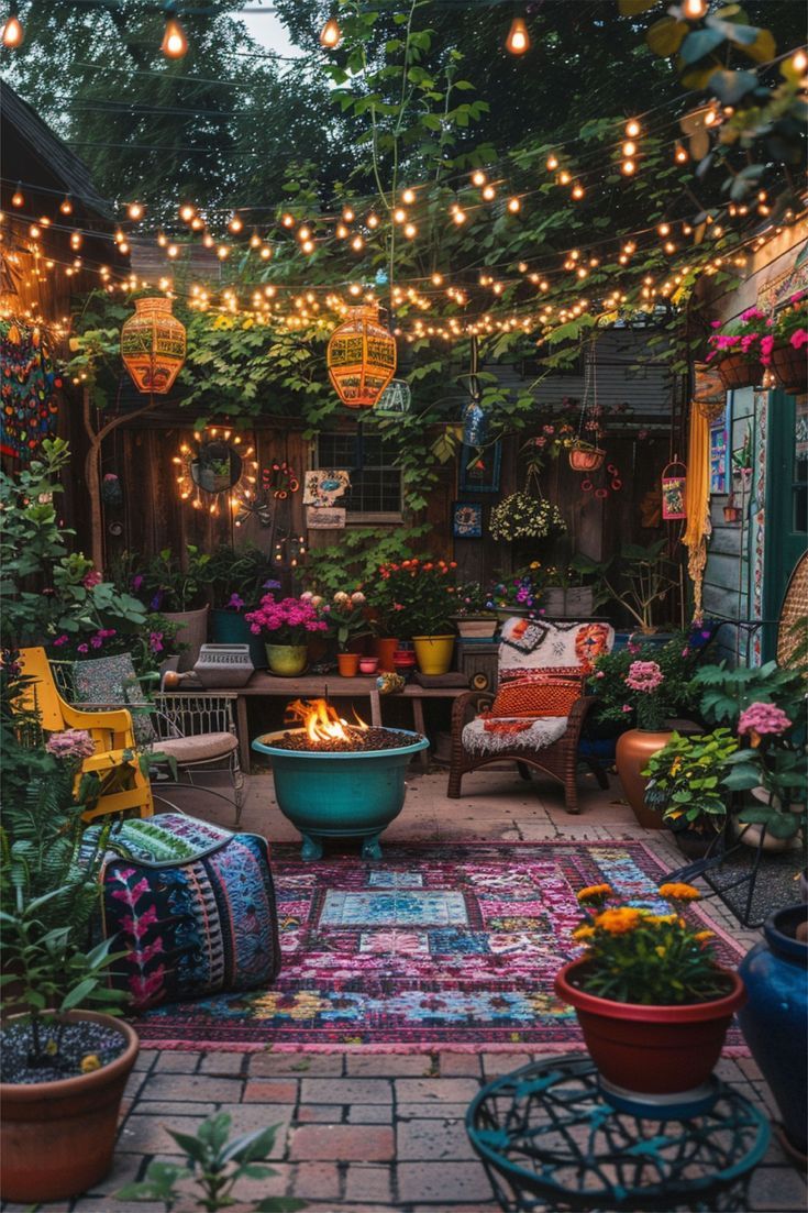 an outdoor patio with potted plants and lights strung over the fire pit, surrounded by greenery