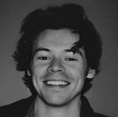 a black and white photo of a young man with his hair pulled back, smiling at the camera