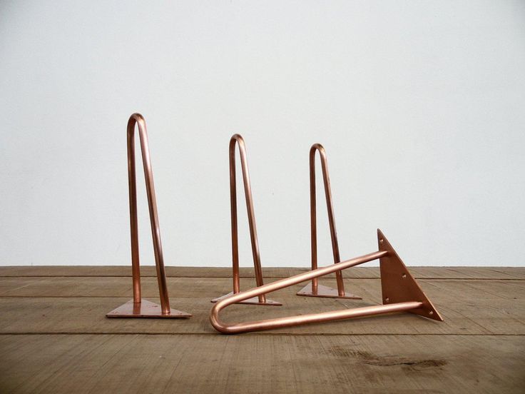 three copper colored metal objects sitting on top of a wooden floor