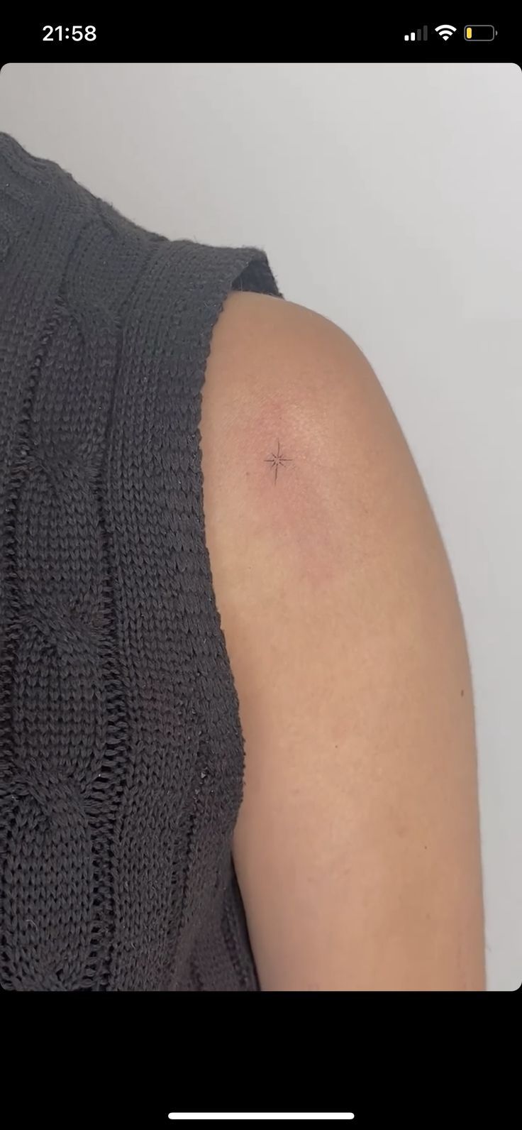 the back of a woman's shoulder with a small star tattoo on her left arm