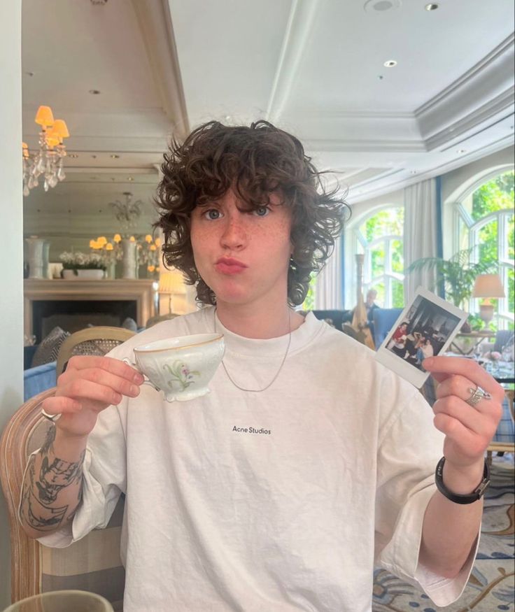 a young man holding a cup and looking at the camera