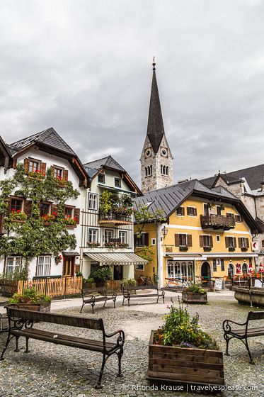 an old european village with many buildings and benches in the foreground, on a cloudy day