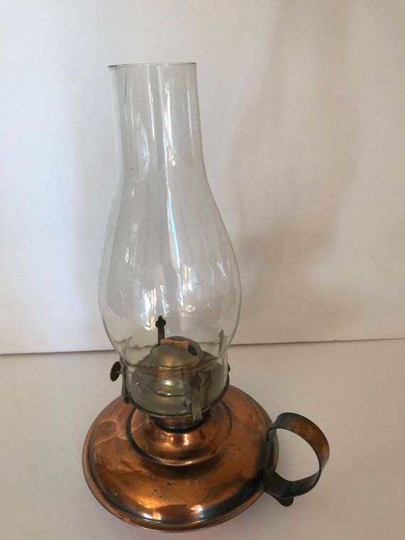 a glass vase sitting on top of a metal stand next to a white wall and a pair of scissors