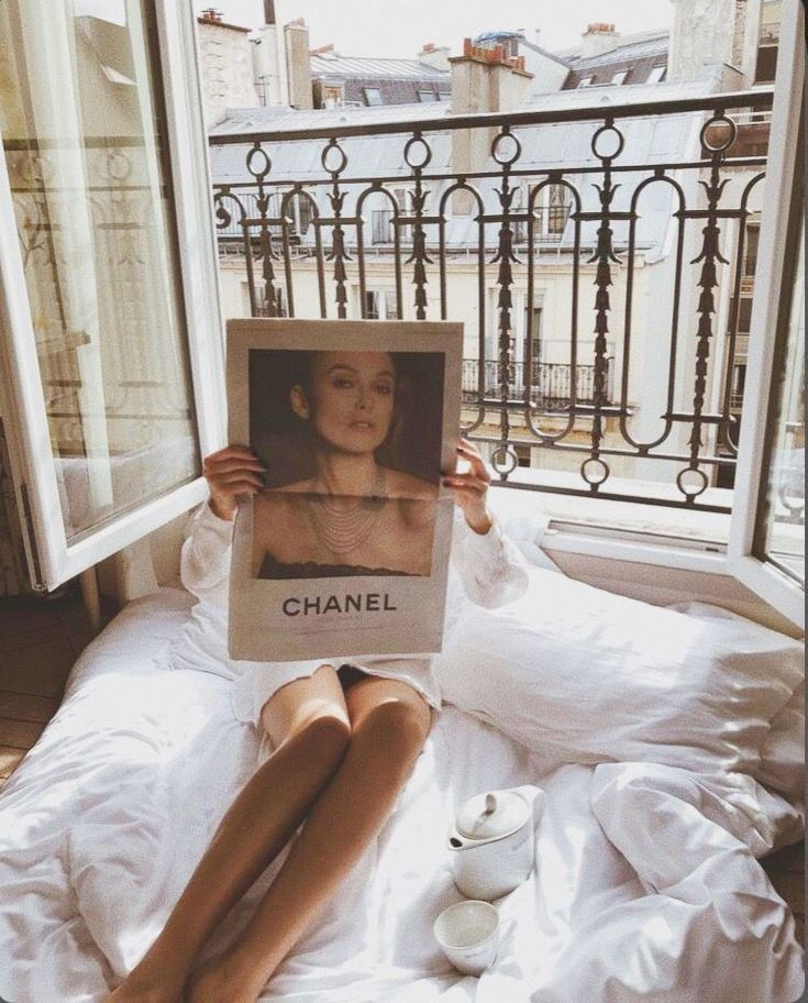 a woman sitting on top of a bed holding up a photo